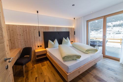 a bedroom with a bed and a desk and a window at Ganovhof - Deluxe Chalet in San Valentino alla Muta