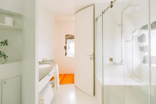a white bathroom with a shower and a sink at Moinho das Feteiras in Feteiras