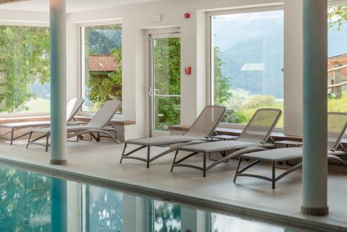 un grupo de sillas sentadas junto a una piscina en Hotel Kirchenwirt, en Dobbiaco
