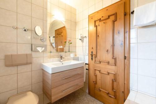 a bathroom with a sink and a wooden door at Hotel Blaue Gams ***S in Ettal