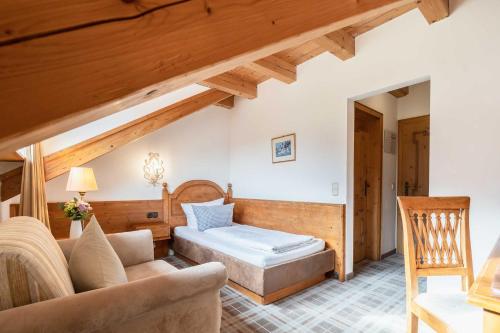 a living room with a bed and a couch at Hotel Blaue Gams ***S in Ettal