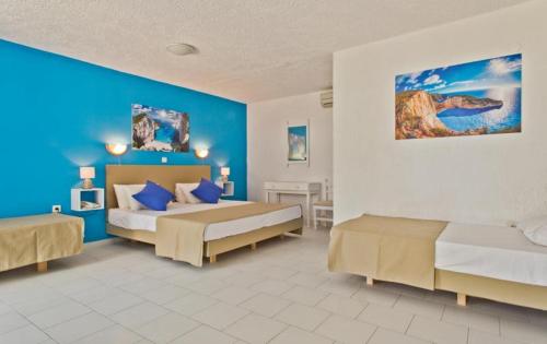1 dormitorio con 2 camas y pared azul en Bluu Bahari Hotel, en Karpathos