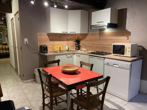 a kitchen with a red table and chairs and a microwave at A la petite maison de village in Sabarat