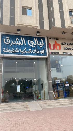 ein Gebäude mit einem blauen Schild auf der Vorderseite in der Unterkunft شقق ليالي الشرق للوحدات 3 in Al-Hasa