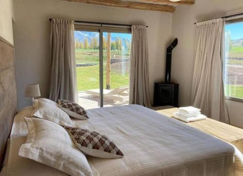 een slaapkamer met een groot bed en een groot raam bij La Carrera Villas, Atamisque. Tupungato, Mendoza. in Ciudad Lujan de Cuyo