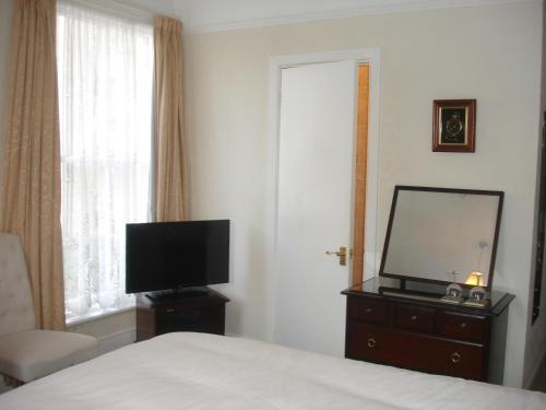 a bedroom with a bed and a flat screen tv at Dunedin Guest House in Penzance