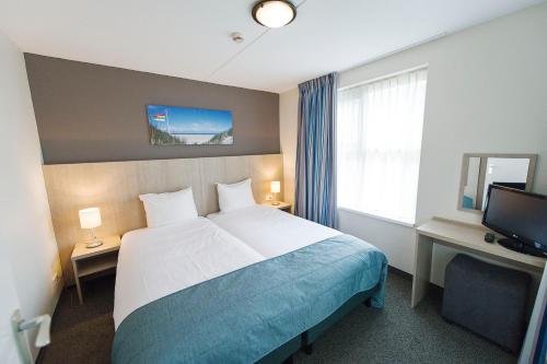 a hotel room with a bed and a television at Hotel Bornholm in West-Terschelling