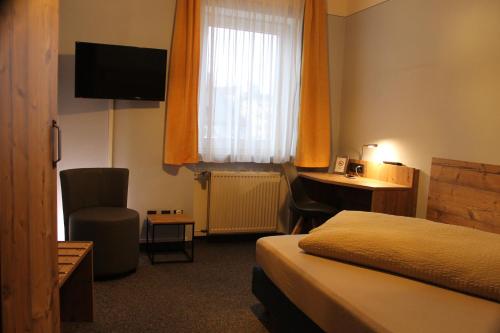 ゼルビッツにあるGasthof Goldene Kroneのベッド、デスク、窓が備わるホテルルームです。