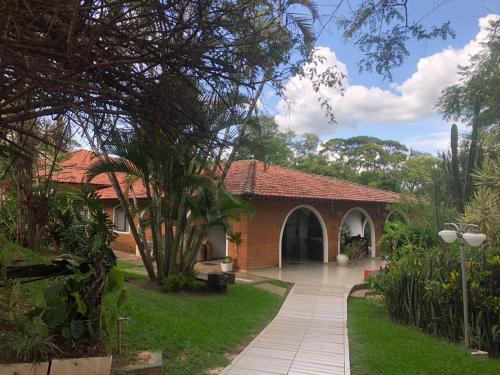 a brick house with a walkway in a yard at Palace Hotel Jacarezinho in Jacarèzinho