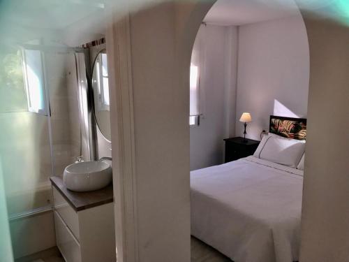 sypialnia z białym łóżkiem i umywalką w obiekcie Residencial las Flores Marbella w Marbelli
