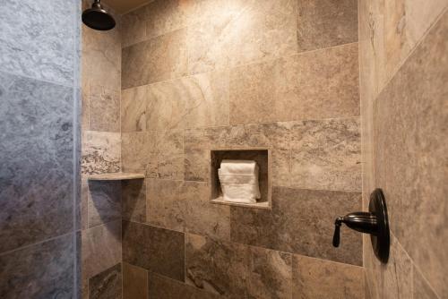 a bathroom with a shower with a stone wall at Stunning Zephyr Mountain Lodge Condo Overlooking The Village Plaza condo in Winter Park