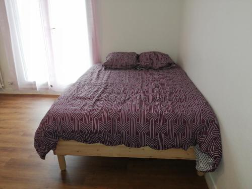a bed with a purple comforter in a room at Chaleureux studio tout confort in Orléans