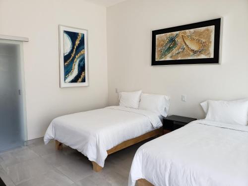 2 camas en una habitación con paredes blancas en Hotel CaLu 21 en La Laguna, Santa María del Oro en Santa María del Oro