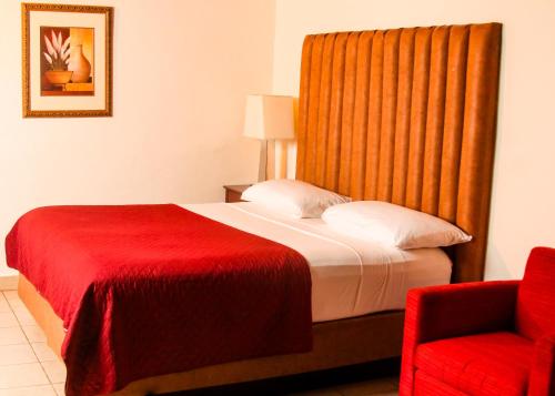 a hotel room with a bed and a red chair at The Stafford Lodge in Freetown