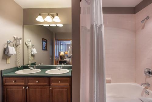 ein Badezimmer mit zwei Waschbecken, einer Badewanne und einem Spiegel in der Unterkunft Lovely Zephyr Mountain Lodge Condo with Mountain Slope Views condo in Winter Park