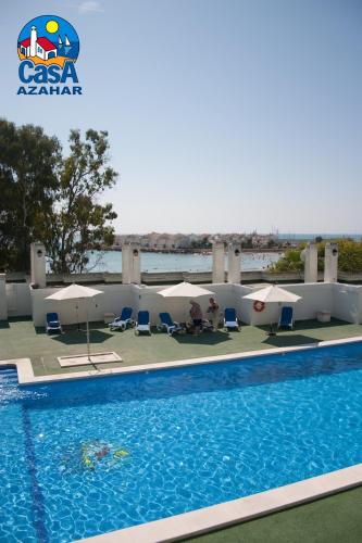 a swimming pool with umbrellas and chairs next to the water at Apartamentos Marino Casa Azahar in Alcossebre