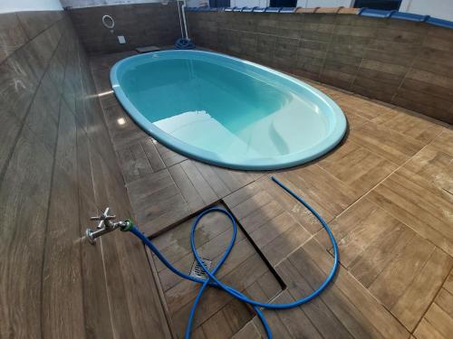 een blauwe badkuip met een tuinslang op een houten vloer bij 0005.02 - Maranduba - Chalé - 1 Dorm - 6 Pess - 3 Quadras Do Mar - Piscina Coletiva - WIFI - Ar Condicionado in Ubatuba