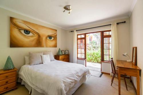 um quarto com uma cama, uma secretária e uma janela em Unique Hout Bay House em Hout Bay