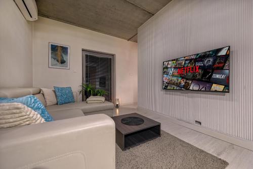 a living room with a couch and a tv on the wall at Apartamenty Jagiełły in Łódź