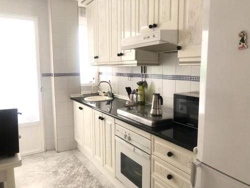 kuchnia z białymi szafkami i czarnym blatem w obiekcie Apartamento Bahía Jardín w mieście La Herradura