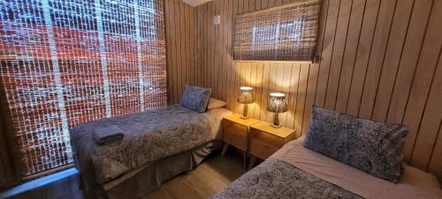 um pequeno quarto com 2 camas e uma janela em Cabaña en Laguna Azul Patagonia Bagual em Torres del Paine