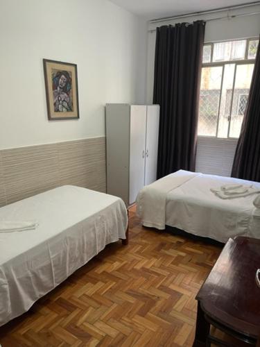 a bedroom with two beds and a window at Comodidade e Segurança no Centro in Belo Horizonte