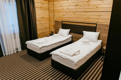two beds in a room with wooden walls at Eco Hotel Tan Tengri in Kostanay