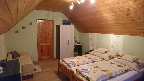 a bedroom with two beds and a wooden ceiling at Zalakaros Panoráma Apartmanok in Zalakaros