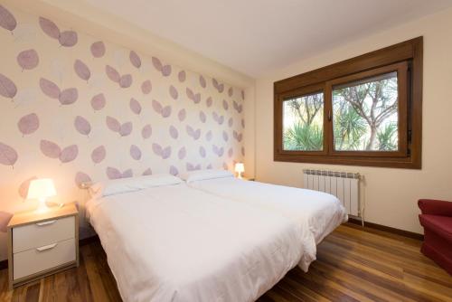 een slaapkamer met een wit bed en een raam bij Casa de Sabela in Culleredo