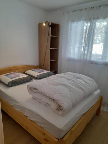 une chambre avec un lit avec des draps blancs et une fenêtre dans l'établissement Appartement 4 à 6 personnes - Station La Joue du Loup - Chalet d'Aurouze, 150m des remontées, à Saint-Étienne-en-Dévoluy