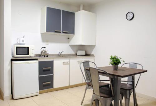 a kitchen with a table and chairs and a microwave at Soltigua Apart Hotel Mendoza in Mendoza