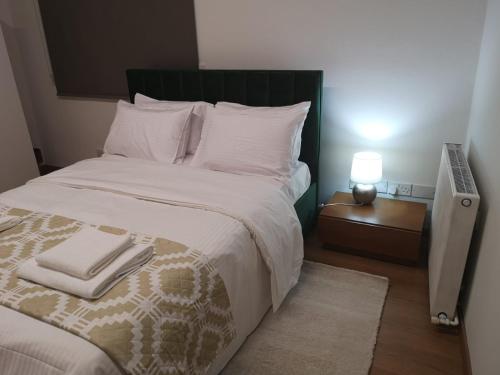 1 dormitorio con 1 cama grande con sábanas y almohadas blancas en KALIDONIA RESIDENCE Suite Nicosia , Spacious 2 BR suite with office en Nicosia