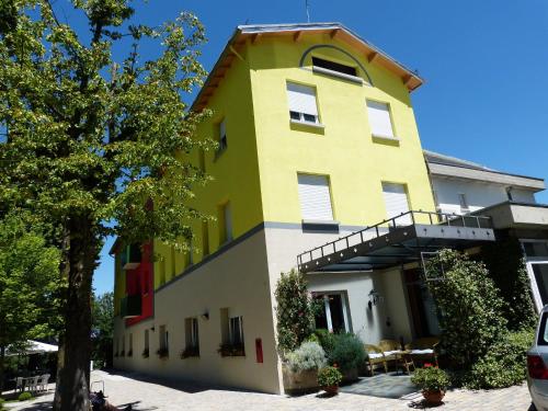 a yellow and white building with a tree at Park Hotel Fantoni in Tabiano