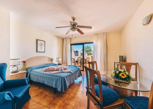a bedroom with a bed and a table and chairs at Sunshine Apartments in San Miguel de Abona