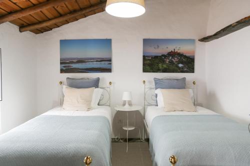 2 camas en una habitación con paredes blancas en Sossego da Carminho en Monsaraz