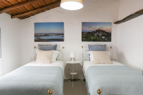 Dos camas en una habitación con paredes blancas. en Sossego da Carminho, en Monsaraz