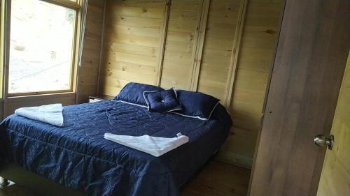 a bedroom with a bed with blue sheets and a window at Chalet el jardín in Ráquira