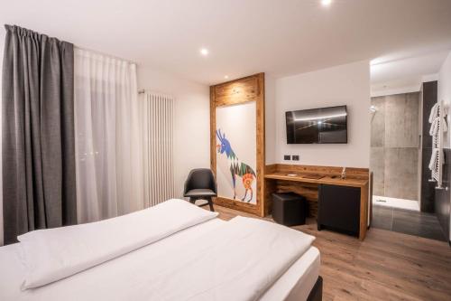 a bedroom with a bed and a desk with a monitor at Croce Bianca Leisure & Spa Hotel in Canazei