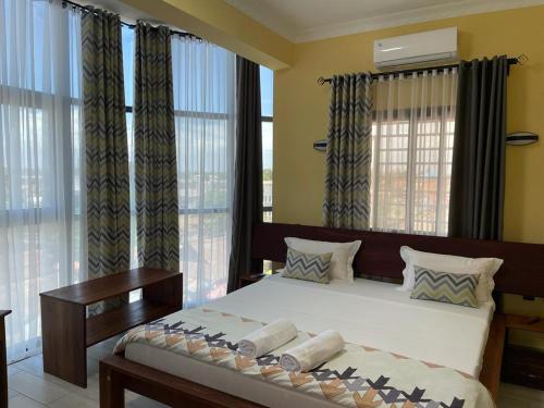 a bedroom with a large bed with curtains and windows at Havana Hôtel in Morondava