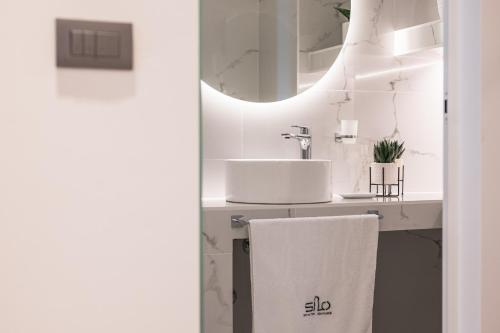 a white bathroom with a sink and a mirror at Silo Luxury Rooms in Nafplio