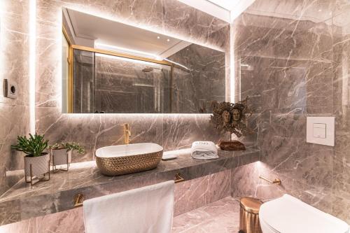 a bathroom with a sink and a toilet and a mirror at Silo Luxury Rooms in Nafplio