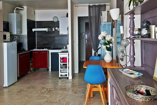 a kitchen with red and blue cabinets and a blue chair at STUDIO MEUBLE Face mer vue imprenable sur la mer, parking et fibre gratuits in Les Sables-d'Olonne