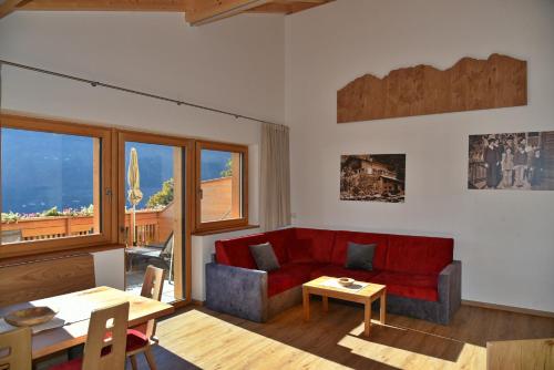 a living room with a red couch and a table at Residence Blumenthalerhof in Lagundo
