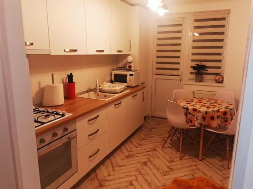 a kitchen with white cabinets and a table and a microwave at Bee Studio in Iernut