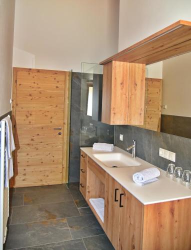 a bathroom with wooden cabinets and a sink at Residence Blumenthalerhof in Lagundo