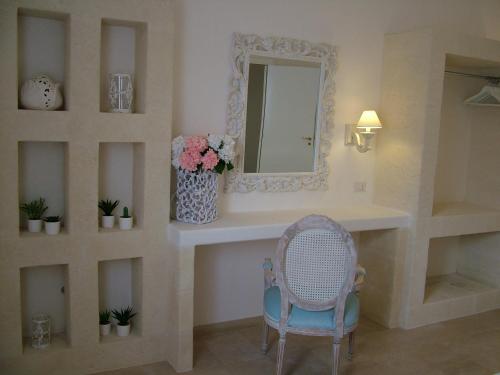 a bathroom with a vanity with a mirror and a chair at Masseria Cappuccini in Ostuni