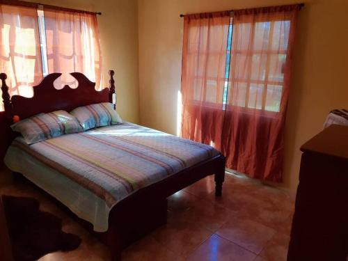 a bedroom with a bed and two windows at Royal Properties Link in Crooked Tree