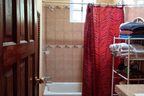 a bathroom with a red shower curtain and a tub at Royal Properties Link in Crooked Tree