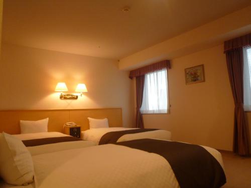 a hotel room with three beds and two windows at Yamagata Kokusai Hotel in Yamagata