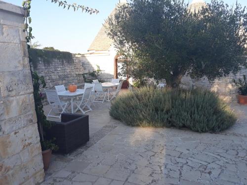 a patio with a table and chairs and a tree at Masseria Cappuccini in Ostuni